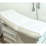 Examination table covered with disposable exam table paper in a clinic exam room