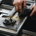 Hands wiping an oily machine tool table with a grey cloth shop towel