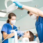 Dental team treating a patient in a dental chair, wearing masks and gloves
