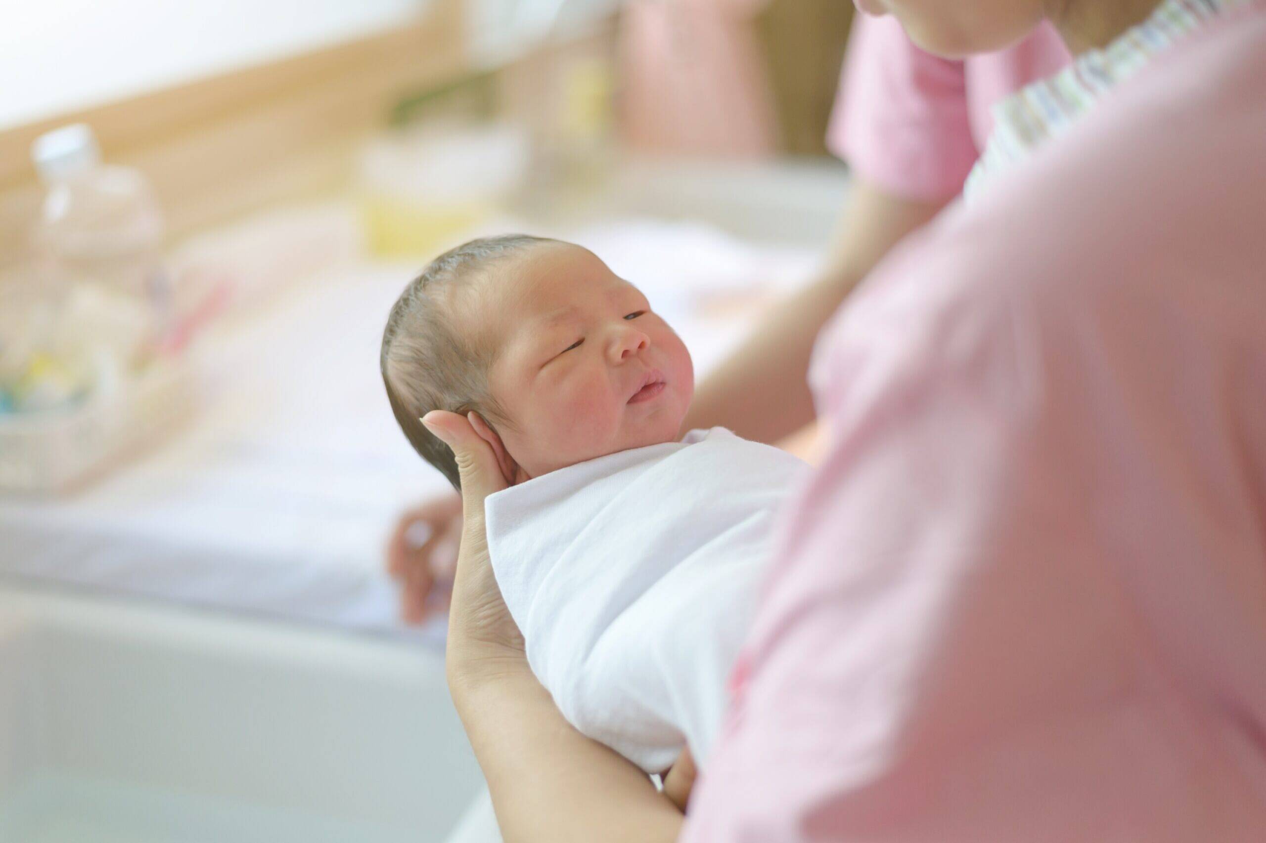 Penjaga taska mendukung bayi baharu lahir yang dibedung, suasana harian penggunaan bekalan kebersihan di kemudahan penjagaan kanak-kanak