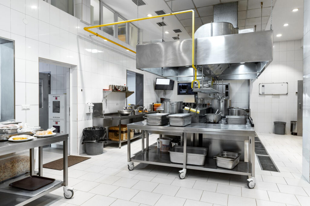 Dapur komersial dengan stesen penyediaan keluli tahan karat, hud ekzos dan longkang lantai tempat FOG memasuki sistem paip