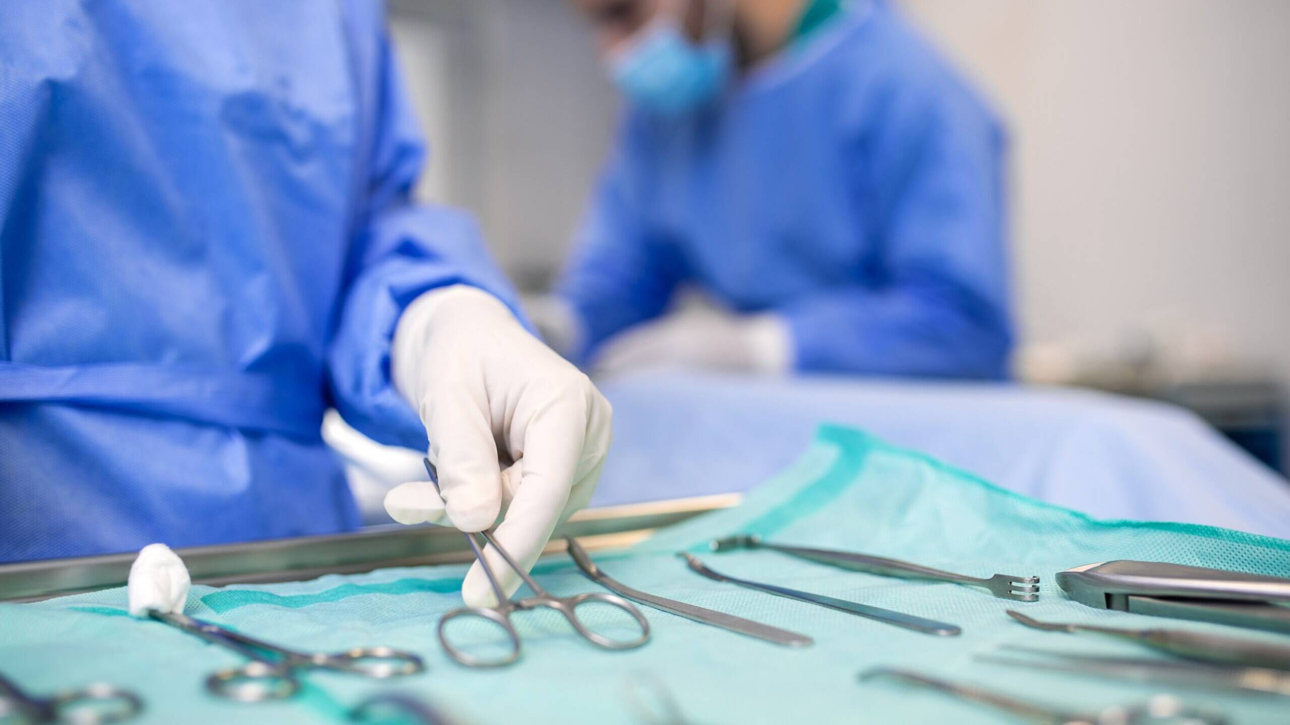 Surgical team in blue disposable gowns with instruments laid on a nonwoven tray wrap, typical uses of SMS fabric