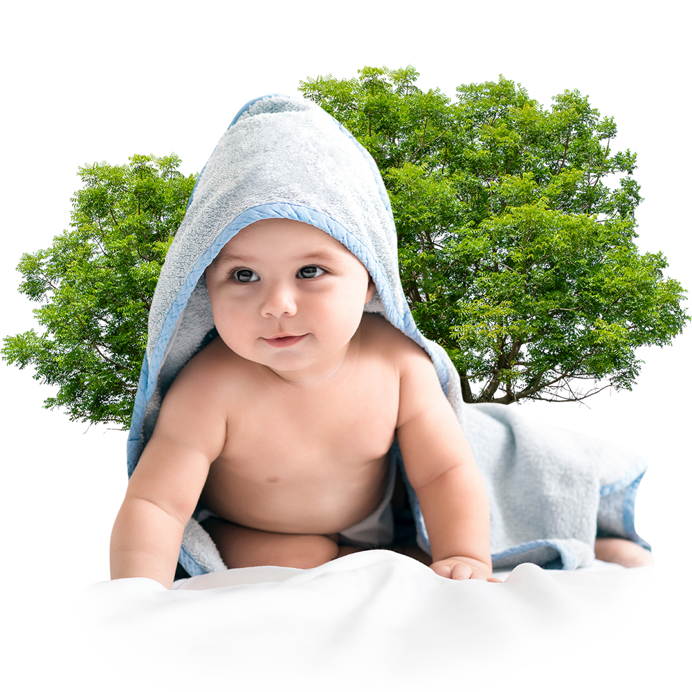 Baby wrapped in a soft nonwoven bath towel against a green tree backdrop