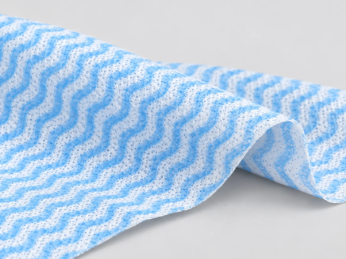 Blue and white wave-pattern nonwoven wiping cloth with an embossed texture
