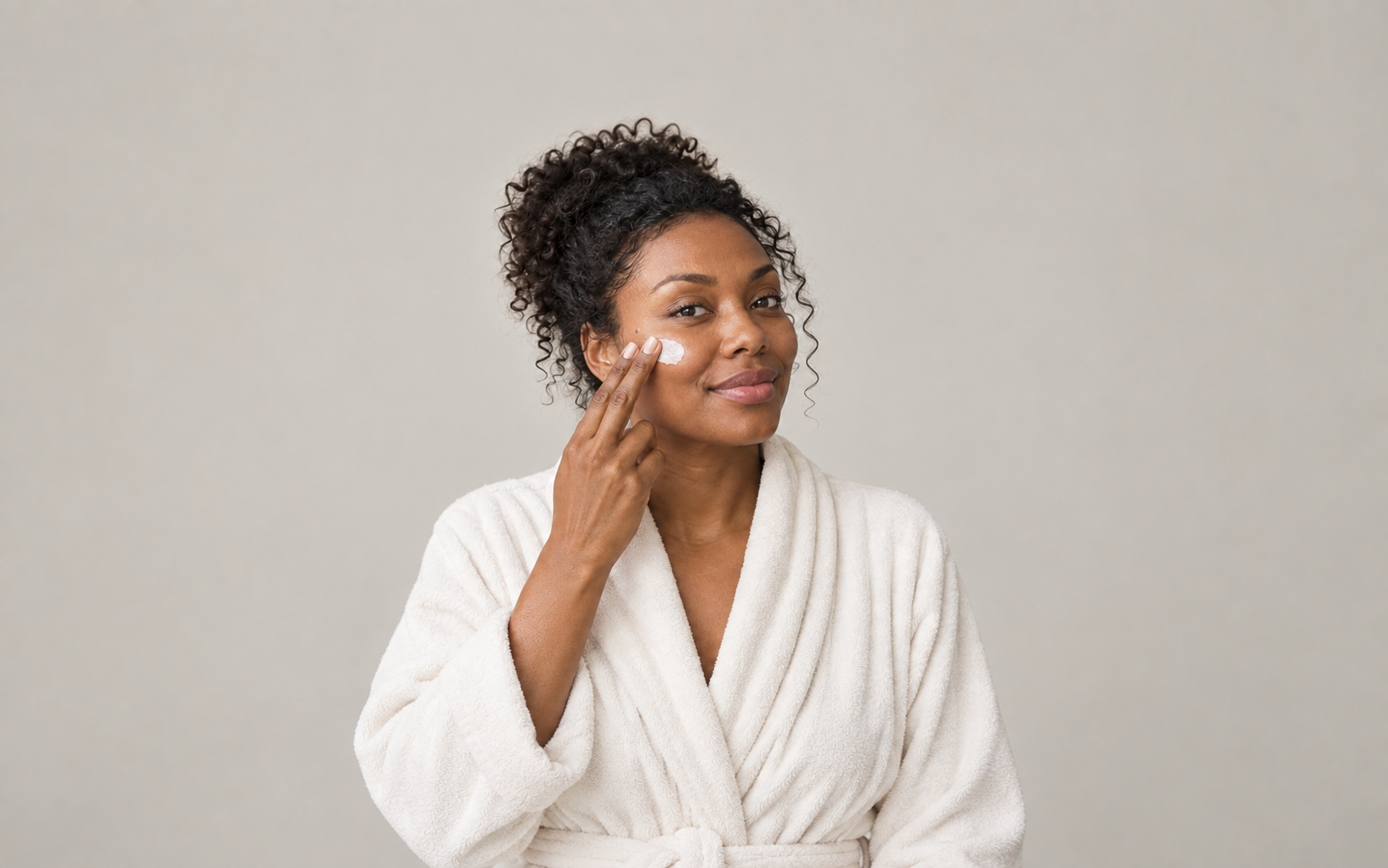 Woman applying moisturiser to her cheek