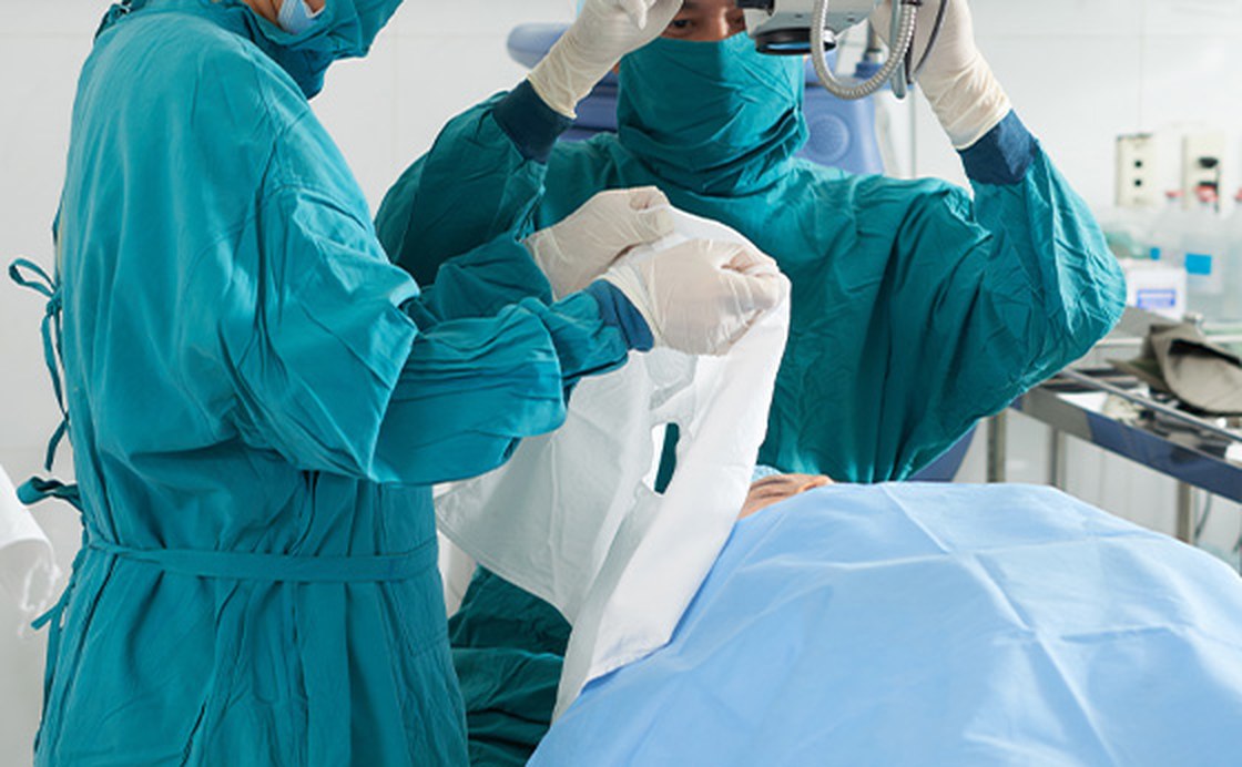 Surgical team applying a sterile drape in an operating room