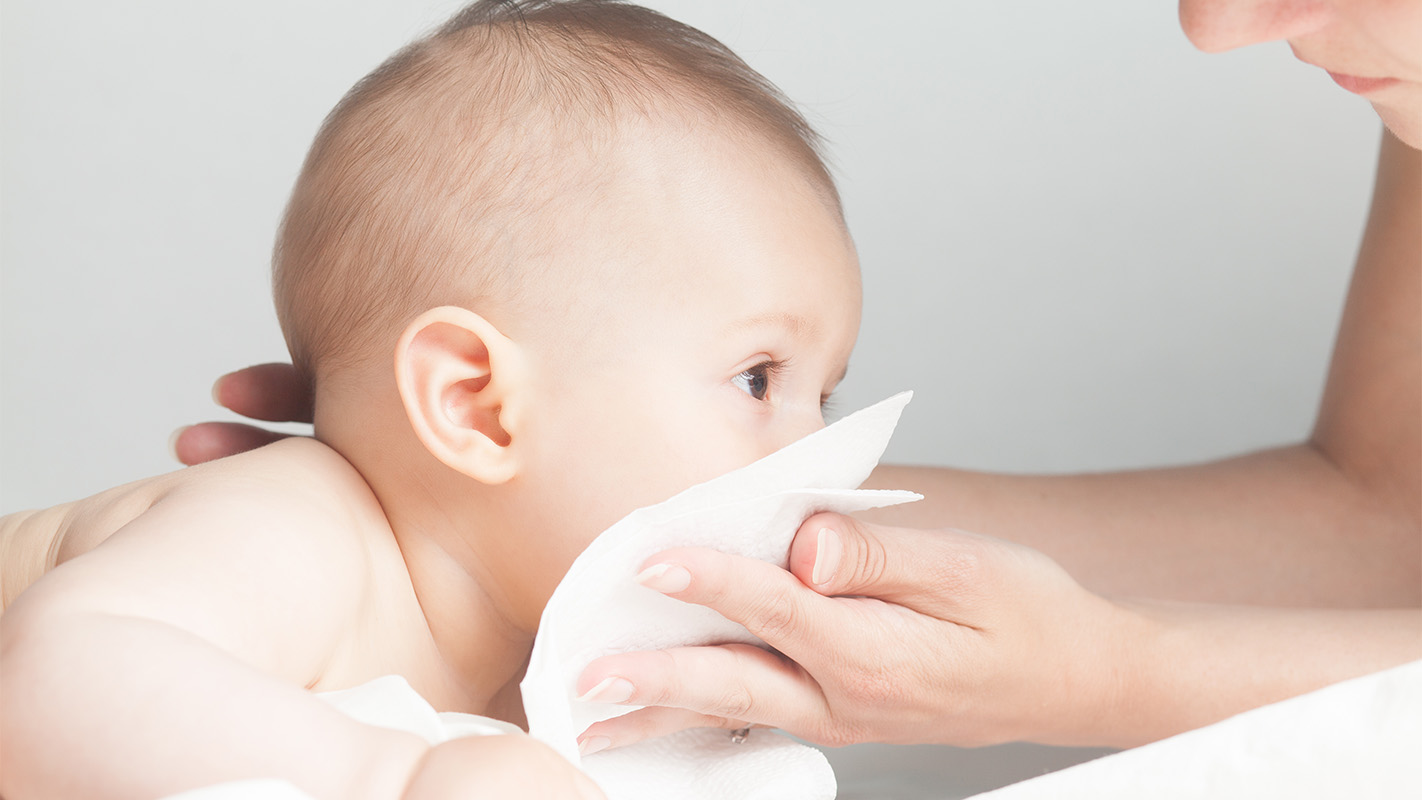 Ibu bapa mengelap muka bayi dengan tisu kering yang lembut